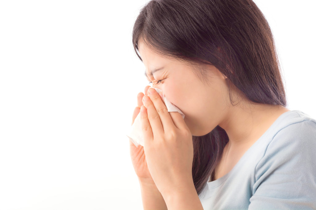an asian girl blowing her nose on a tissue due to sinusitis for the blog do i need sinus surgery