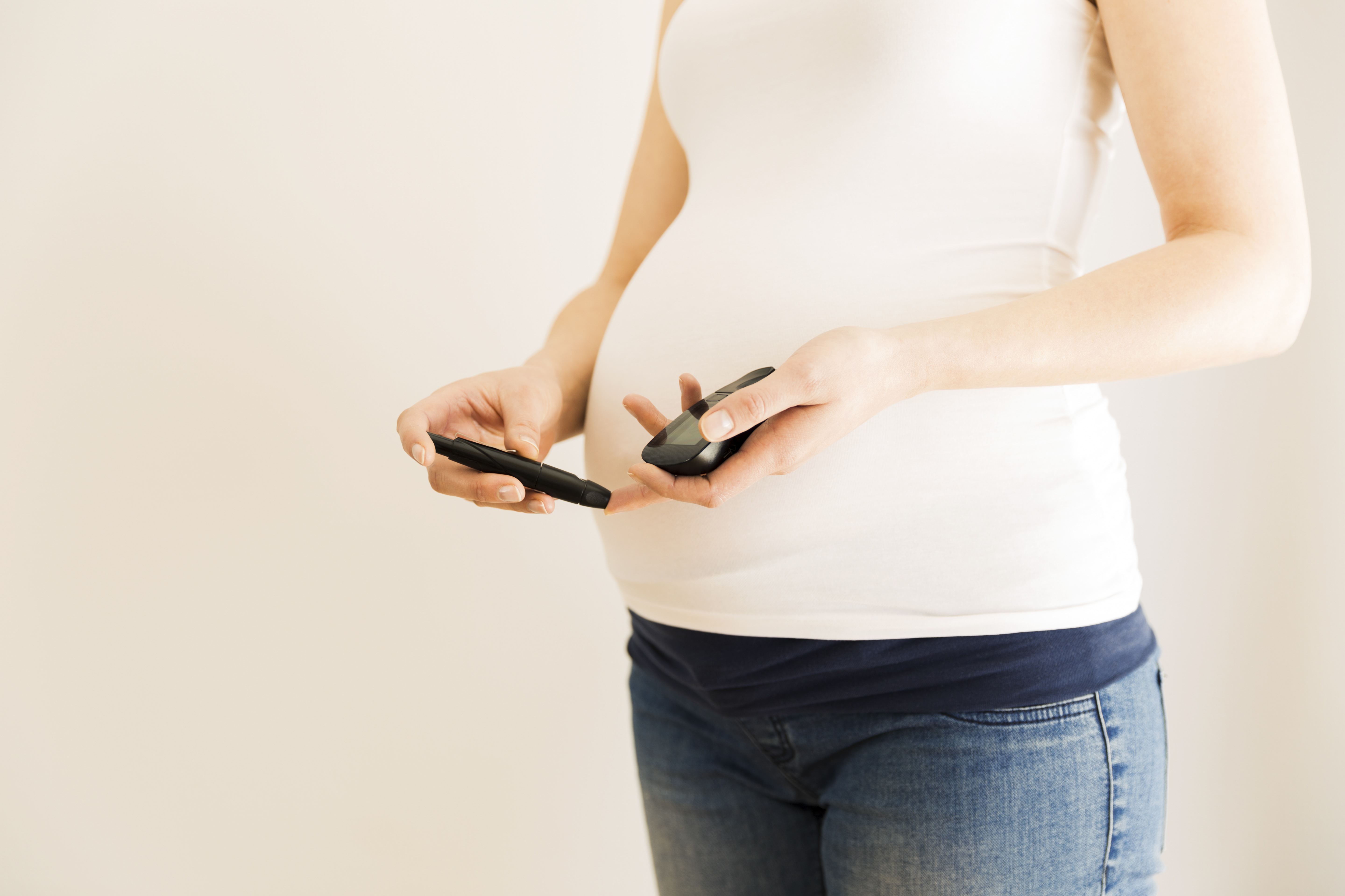 an image of a pregnant lady holding diabetes test controller gestational diabetes mellitus